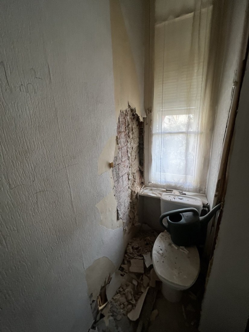 Ancien WC en cours de dépose, faïence retirée jusqu'à la brique