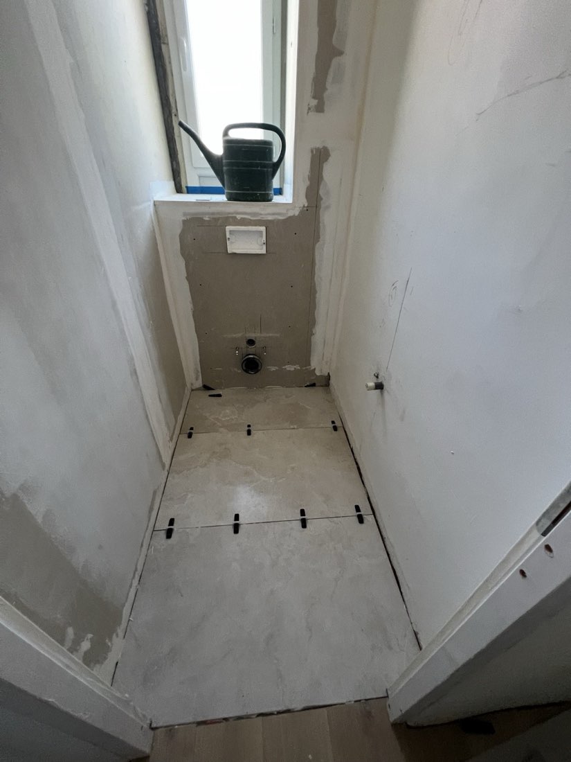 WC en cours de carrelage, receveur et arrivées préparés